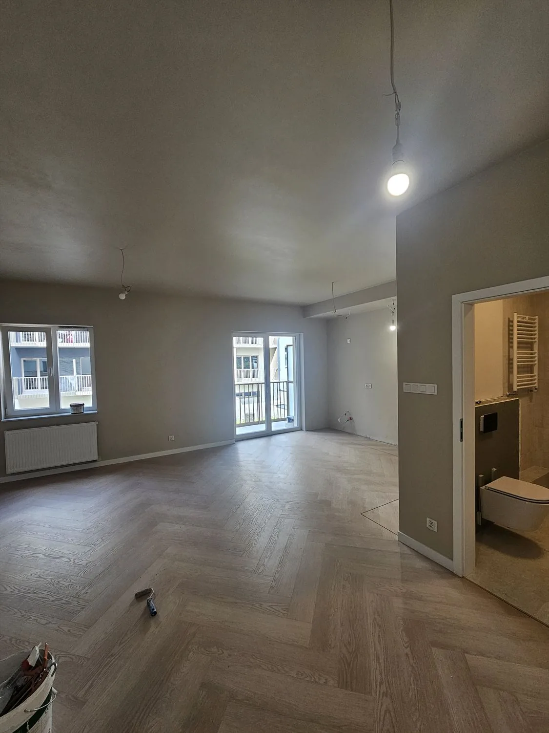 Salon z podłogą w jodełkę i wyjściem na balkon