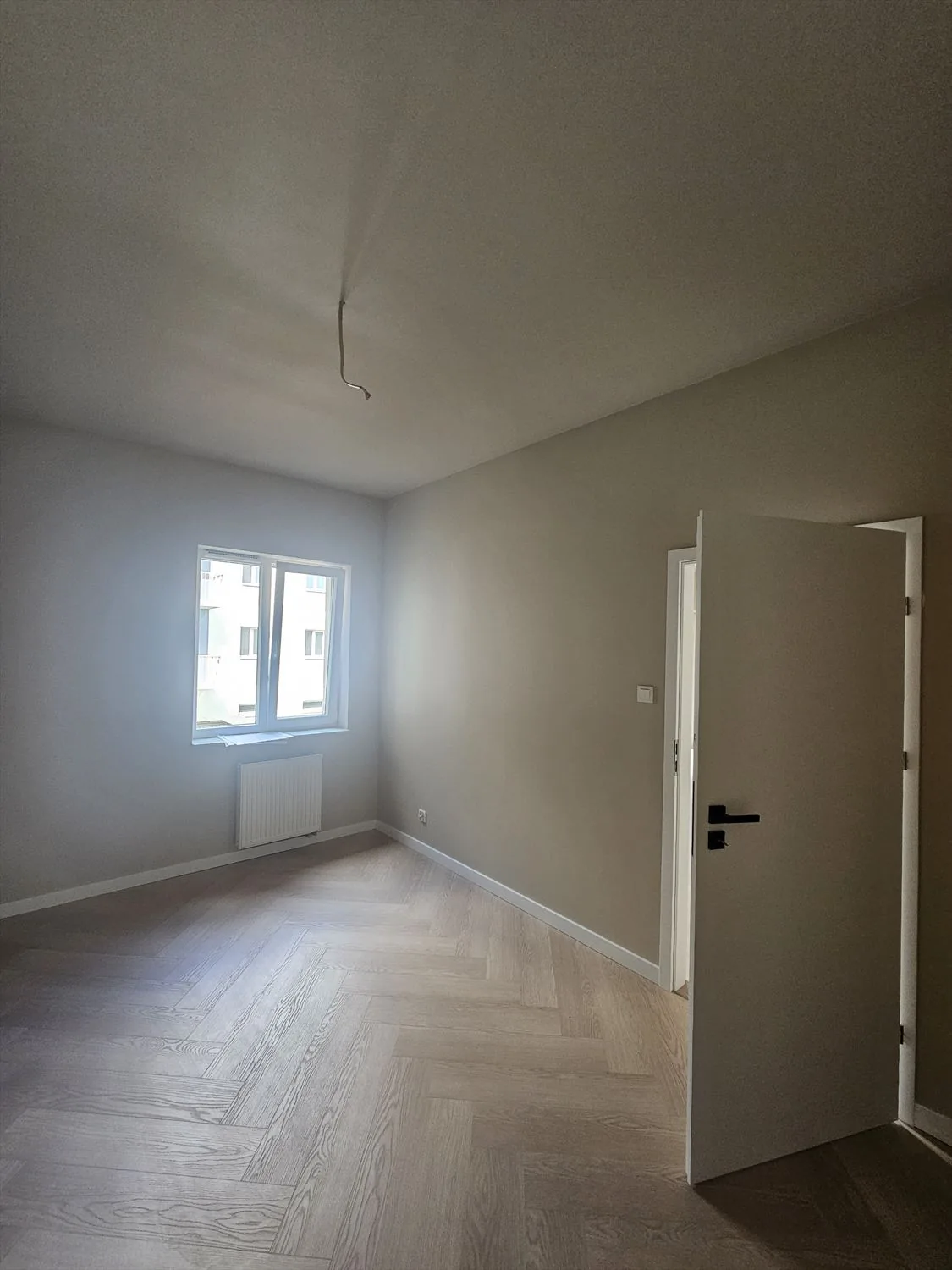 Pokój z podłogą w jodełkę i ciemną zabudową ścienną